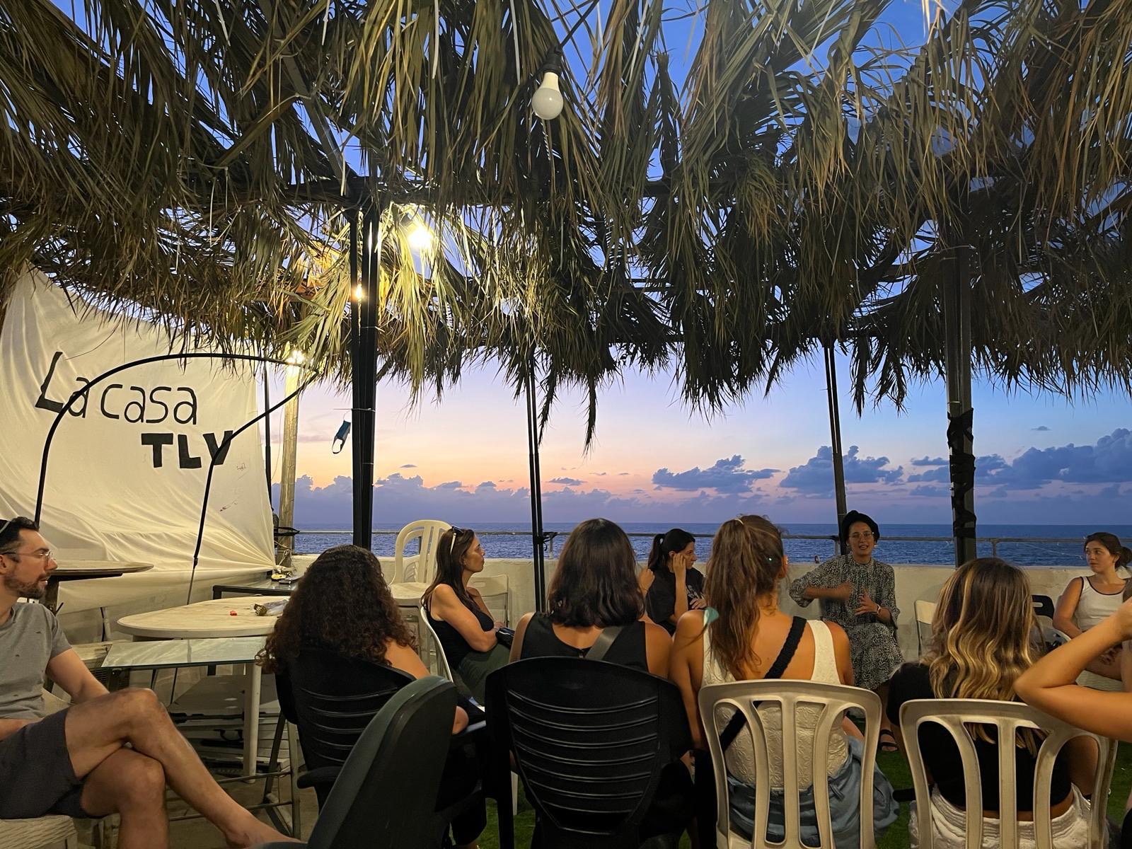 Encuentro de La Casa en una terraza frente al mar, al atardecer